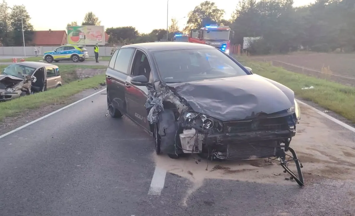 Śmigłowiec ratunkowy ląduje na polnej drodze, obok quada w rowie, ratownicy niosą nosze, wieczorne światło, wiejski krajobraz