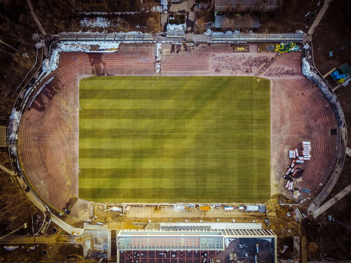 Widok z góry na owalny stadion z zielonym boiskiem otoczonym bieżnią.