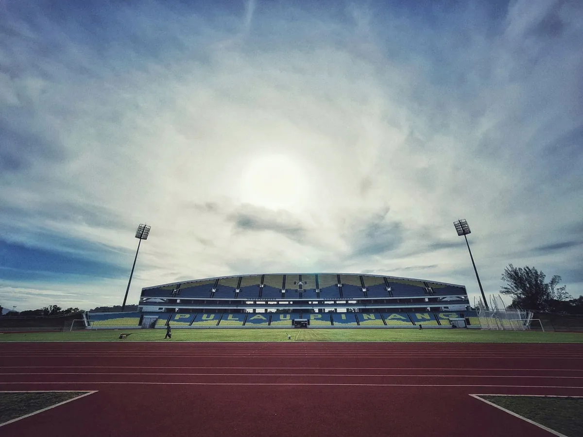 Stadion z bieżnią lekkoatletyczną i boiskiem znajduje się pod zachmurzonym niebem.